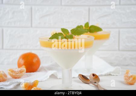 Vanillepanna Cotta mit Mandarinenschicht in einer kleinen portionierten Vase und Fruchtstücke in Weingläsern. Köstliches italienisches Dessert. Stockfoto