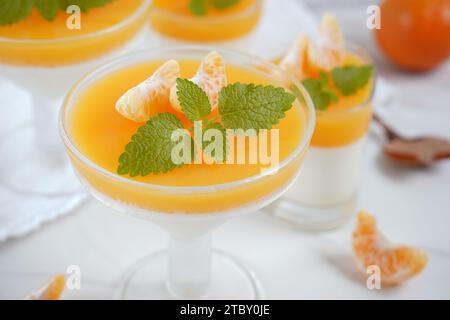 Vanillepanna Cotta mit Mandarinenschicht in einer kleinen portionierten Vase und Fruchtstücke in Weingläsern. Köstliches italienisches Dessert. Stockfoto
