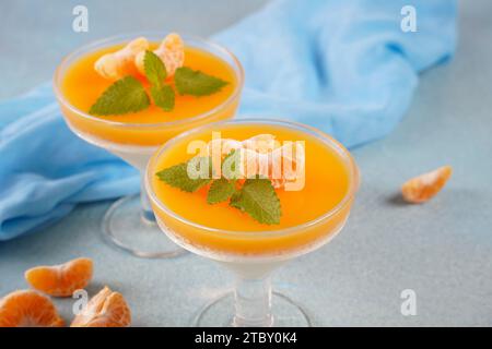 Vanillepanna Cotta mit Mandarinenschicht in einer kleinen portionierten Vase und Fruchtstücke in Weingläsern. Köstliches italienisches Dessert. Stockfoto