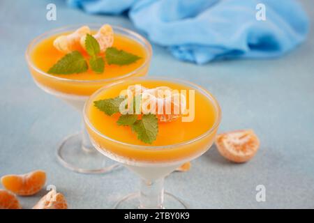 Vanillepanna Cotta mit Mandarinenschicht in einer kleinen portionierten Vase und Fruchtstücke in Weingläsern. Köstliches italienisches Dessert. Stockfoto