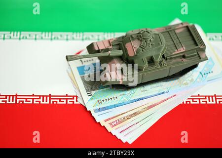 Iranische Armee Spielzeugpanzer-Antrieb auf iranischen Rial-Wechseln auf der Flagge der Islamischen Republik Iran Nahaufnahme Stockfoto