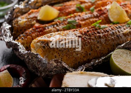 Gegrillter Zuckermais mit geräucherter Paprika Limette und Butter in Alufolie auf Küchentisch glutenfreie gesunde Lebensmittel Hintergrund Stockfoto