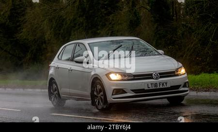 Milton Keynes, Bucks, UK - 9. Dezember 2023: 2018 weißes Volkswagen Polo-Auto fährt auf nasser Straße, im Regen mit Scheinwerfern an Stockfoto