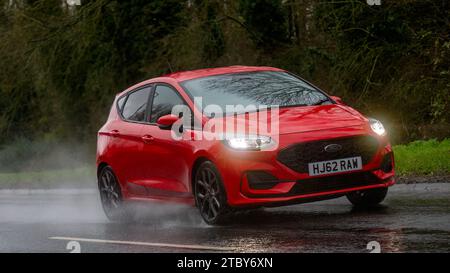 Milton Keynes, Bucks, UK - 9. Dezember 2023: 2022 Ford Fiesta Auto fährt auf nasser Straße, im Regen mit Scheinwerfern an Stockfoto
