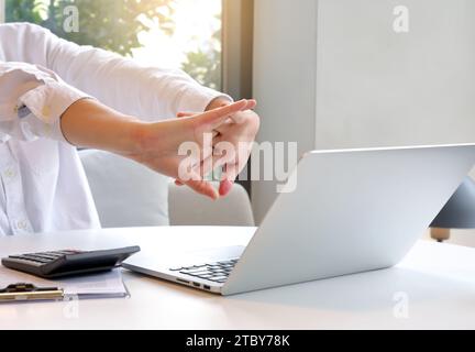 Geschäftsfrau, die sich in ihrem Stuhl im Büro mit gefesselten Händen entspannt und sich dehnt Stockfoto