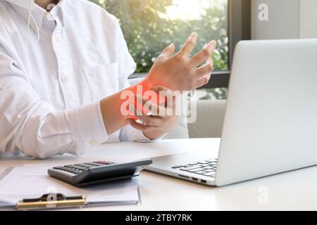 Frau, die auf dem Laptop schreibt, hält ihr schmerzhaftes Handgelenk mit Karpaltunnel (Hervorheben der schmerzhaften Stelle in Rot) Stockfoto