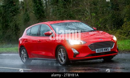 Milton Keynes, Bucks, UK - 13. Dezember 2023: 2019 rotes Ford Focus Auto fährt auf nasser Straße, im Regen und mit Scheinwerfern Stockfoto