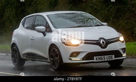 Milton Keynes, Bucks, UK - 13. Dezember 2023: 2019 weißes Renault Clio Auto fährt auf nasser Straße, im Regen und mit Scheinwerfern Stockfoto