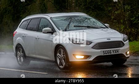 Milton Keynes, Bucks, UK - 9. Dezember 2023: 2016 weißes Ford Focus Auto fährt auf nasser Straße, im Regen mit Scheinwerfern Stockfoto
