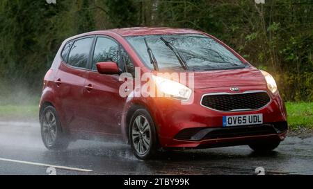 Milton Keynes, Bucks, UK - 9. Dezember 2023: 2016 rotes Kia Venga Auto fährt auf nasser Straße, im Regen und mit Scheinwerfern an Stockfoto
