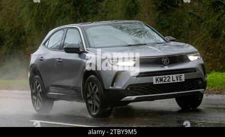 Milton Keynes, Bucks, UK - 9. Dezember 2023: 2022 graues Vauxhall Mokka Auto fährt auf nasser Straße, im Regen und mit Scheinwerfern Stockfoto