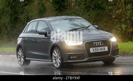 Milton Keynes, Bucks, UK - 9. Dezember 2023: 2015 graues Audi A1 Dieselauto fährt auf nasser Straße, im Regen und mit Scheinwerfern Stockfoto