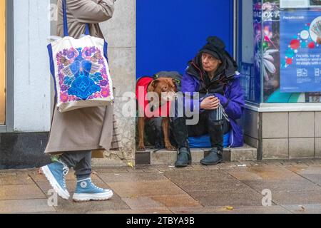 Bettler mit Hund in Preston, Großbritannien. Dezember 2023. Schlafender Rough zu Weihnachten. Geschäfte, Shopper, Einkaufen an einem nassen Tag in der Fishergate High Street. Stockfoto