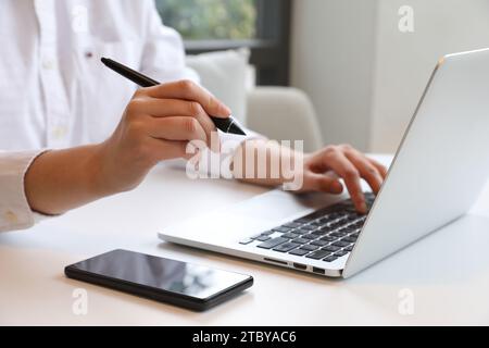 Eine Frau, die einen Touchpen hält und erklärt, während sie eine Videokonferenz auf einem Laptop auf ihrem Schreibtisch abhält Stockfoto