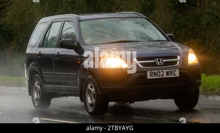 Milton Keynes, Bucks, Großbritannien - 9. Dezember 2023: 2002 Honda CR-V Auto fährt auf nasser Straße, im Regen und bei eingeschalteten Scheinwerfern Stockfoto