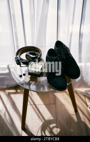 Die Box mit Eheringen steht auf einem Glastisch neben den Bräutigam-Schuhen und Manschettenknöpfen Stockfoto