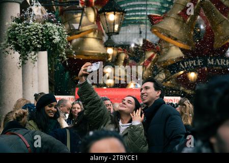 Leute, die den falschen Schneefall in London genießen, Covent Garden Stockfoto