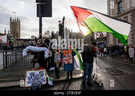 London, Großbritannien. 9. Dezember 2023. Die Menschen versammeln sich zu einer Kundgebung auf dem Parlamentsplatz während eines Nationalmarsches für Palästina in Solidarität mit dem palästinensischen Volk und fordern einen sofortigen Waffenstillstand im israelischen Hamas-Krieg, der mit dem Angriff der Hamas auf Israel am 7. Oktober begann. Die USA haben ein Veto gegen eine Waffenstillstandsabstimmung des UN-Sicherheitsrates eingelegt, wobei sich Großbritannien der Stimme enthalten hat. Quelle: Stephen Chung / Alamy Live News Stockfoto