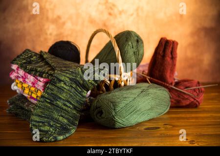 Wollgarn, Stricknadeln und andere Handstrickwerkzeuge auf einem dunklen Holztisch. Stockfoto