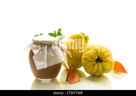 Reife Quittenfrucht mit Marmelade in einem Glas isoliert auf weißem Hintergrund. Herbstrezepte. Stockfoto