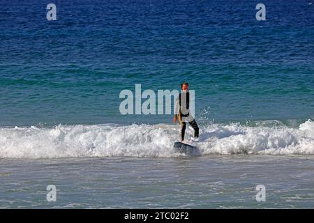 Frau, die am Piedra Beach surft, aufrecht auf dem Surfbrett steht, El Cotillo, Fuerteventura, Kanarischen Inseln, Spanien. Vom November 2023 Stockfoto