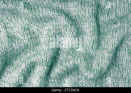 Grüne und weiße Farbe melierte Strickstoff aus Kaschmir-Wolle. Hintergrund von zerknittertem, faltigem Strickgewebe, Textilstruktur, Tuchoberfläche, W Stockfoto