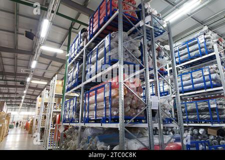 Übersicht über ein großes, modernes Industrielager, in dem Produkte in Kartons, Taschen und Rollen gelagert werden. Stockfoto