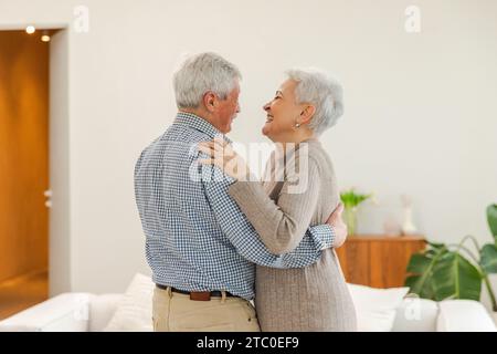 Bleiben Sie in Bewegung. Ein romantisches älteres Ehepaar, das zu Hause zu Musik tanzt. Glückliche lächelnde Familie pensionierter Mann Frau Ehemann Frau, die Spaß hat, die Zeit zusammen zu genießen. Familie Moment Liebe Pflege Stockfoto