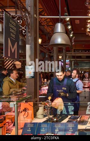 MADRID SPANIEN - 09. DEZEMBER 2023: Ladenassistent schneidet Schinken am Marktstand San Miguel in Madrid Spanien Stockfoto