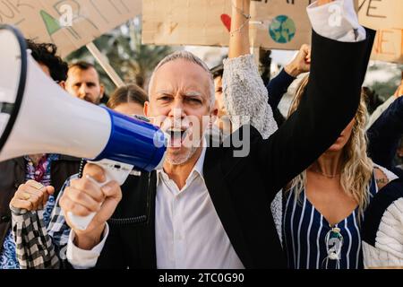 Hochrangiger Aktivist mit einem Megaphon, der gegen den Klimawandel protestiert Stockfoto
