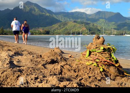 Ein älteres Ehepaar spaziert entlang der Küste mit Sandhügeln, die in Seetang gehüllt sind, in der Nähe der Hanalei Bay auf Kauai, Hawaii Stockfoto