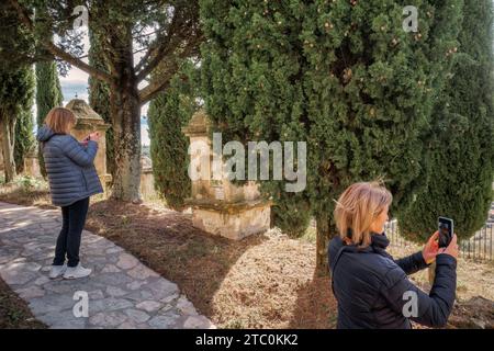 Zwei Frauen, die die Tortur der Via Crucis mit Zypressen in der Stadt Culla fotografieren, erklärten sich als die schönste in Spanien, Castellón, Spanien. Stockfoto