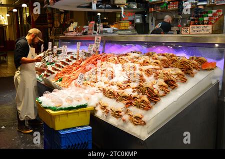 Ein Marktverkäufer untersucht den Fang von frischem Fisch und packt ihn auf dem Pike Place Market in Seattle in Eis Stockfoto