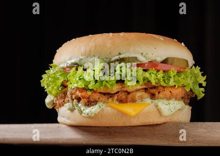 Perfekter leckerer Cheeseburger mit großem Huhn auf Holztisch auf braunem Hintergrund Stockfoto