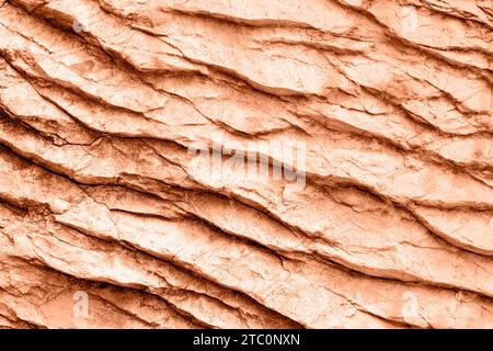 Pfirsichfarbenes Gestein oder eine Steinoberfläche. Hintergrund, Textur. Farbe des Jahres 2024 - Peach Fuzz. Stockfoto