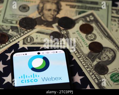 In dieser Fotoabbildung ist ein Webex by Cisco Logo auf einem Smartphone mit US-Dollar-Banknoten und -Münzen im Hintergrund zu sehen. Stockfoto