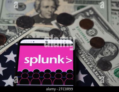 Deutschland. Dezember 2023. In dieser Fotoabbildung wird ein Splunk-Teil des Cisco-Logos auf einem Smartphone mit US-Dollar-Banknoten und -Münzen im Hintergrund angezeigt. (Credit Image: © Igor Golovniov/SOPA images via ZUMA Press Wire) NUR REDAKTIONELLE VERWENDUNG! Nicht für kommerzielle ZWECKE! Stockfoto