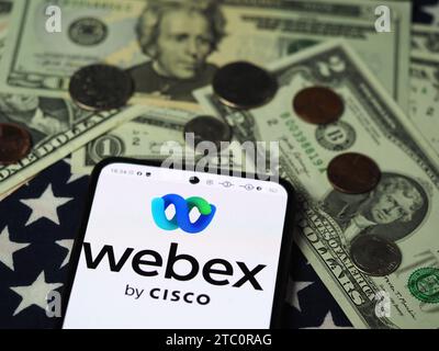 Deutschland. Dezember 2023. In dieser Fotoabbildung ist ein Webex by Cisco Logo auf einem Smartphone mit US-Dollar-Banknoten und -Münzen im Hintergrund zu sehen. (Foto von Igor Golovniov/SOPA Images/SIPA USA) *** ausschließlich für redaktionelle Nachrichten *** Credit: SIPA USA/Alamy Live News Stockfoto
