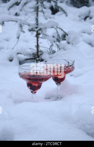Zwei Gläser Rosé-Champagner-Cocktail mit Beeren und Rosmarin auf Schnee Stockfoto