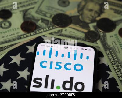 Deutschland. Dezember 2023. In dieser Fotoabbildung ist ein Slido-Teil des Cisco-Logos auf einem Smartphone mit US-Dollar-Banknoten und -Münzen im Hintergrund zu sehen. (Credit Image: © Igor Golovniov/SOPA images via ZUMA Press Wire) NUR REDAKTIONELLE VERWENDUNG! Nicht für kommerzielle ZWECKE! Stockfoto