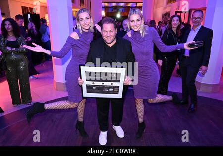 München, Deutschland. Dezember 2023. Die Models Nina und Julia Meise stehen mit dem Filmemacher Mayk Azzato bei der Feier des 100. Preises des Filmemachers Azzato im „The Charles“ Hotel Credit: Felix Hörhager/dpa/Alamy Live News Stockfoto