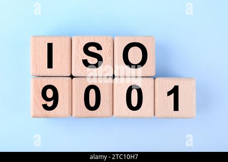 Internationale Organisation für Normung. Holzwürfel mit der Abkürzung ISO und der Nummer 9001 auf hellblauem Hintergrund, flach angelegt Stockfoto