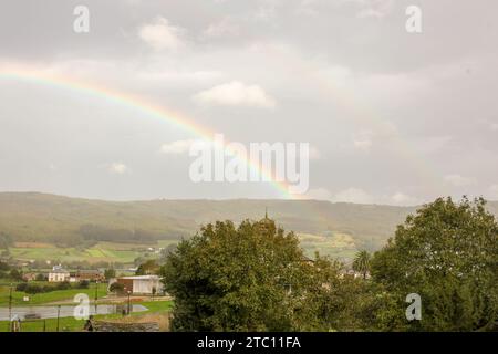 Verzaubertes Homestead: Regenbogen über einem Weißen Haus in den Bergen Stockfoto