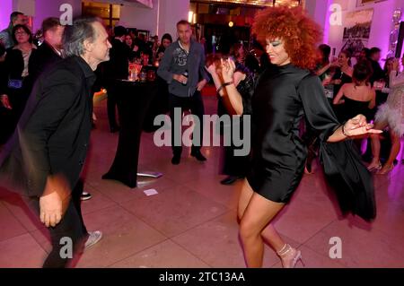 München, Deutschland. Dezember 2023. Diana Schneider, Schauspielerin und Sängerin, und Schauspieler Ralf Bauer tanzen bei der Feier des 100. Preises des Filmemachers Azzato im Hotel „The Charles“. Quelle: Felix Hörhager/dpa/Alamy Live News Stockfoto