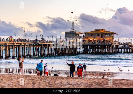 Touristen machen Fotos am Santa Monica Beach, mit Santa Monica Pier im Hintergrund, Sommernachmittag in Südkalifornien Stockfoto