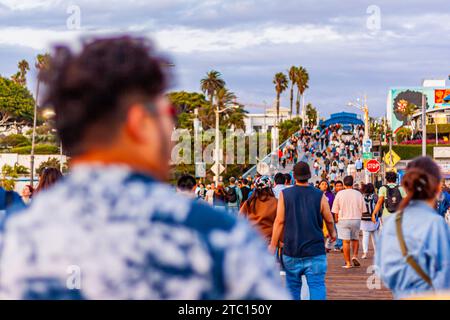 Touristen laufen am Santa Monica Pier, Santa Monica, Kalifornien, bei Sonnenuntergang. Berühmtes Urlaubsziel in Südkalifornien. Stockfoto
