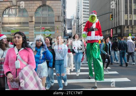 New York, Usa. Dezember 2023. Ein SantaCon-Teilnehmer mit Grinch-Kostüm geht über die Straße. In Manhattan, New York City, versammelten sich Schwärmer, die als Weihnachtsmann verkleidet waren, zur SantaCon, einem jährlichen Weihnachtsbummel, der Geld für wohltätige Zwecke sammelte. Die Spender erhielten Zutritt zu teilnehmenden Veranstaltungsorten wie Bars und Clubs. (Foto: Jimin Kim/SOPA Images/SIPA USA) Credit: SIPA USA/Alamy Live News Stockfoto