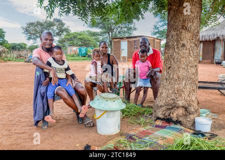 afrikanische Dorffamilie, auf dem Hof vor dem Haus, Hütte mit Strohdach im Hintergrund Stockfoto