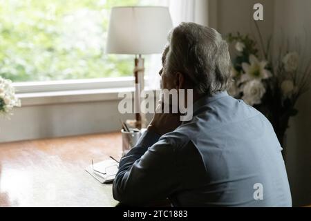Rückansicht eines alten, heilen Mannes beim Betrachten von Fenstern Stockfoto