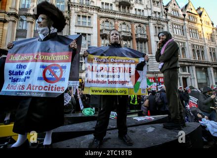 Ein palästinensischer Unterstützer schaut sich Mitglieder von Neturei Karta, einer antizionistischen Sekte der orthodoxen jüdischen Gemeinde, an, während sie an der Demonstration teilnehmen und antizionistische Plakate um den Hals tragen. Tausende von Menschen kommen zusammen, um einen vollständigen Waffenstillstand im Krieg zwischen Israel und der Hamas zu fordern. Obwohl es in Gaza eine Anfeindungspause gab, sagten die Hilfsorganisationen kürzlich, dass es nicht lange genug war, um die 1,1 Millionen Kinder zu erreichen, die dringend Hilfe benötigen. Seit dem 7. Oktober 2023 wurden Tausende von Zivilisten in Gaza und Israel getötet, nachdem nach dem Tod der Hamas Ove ein Krieg ausgelöst worden war Stockfoto